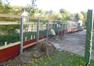 Construction d'un mur de soutien surplombé d'une palissade de béton structuré et placement d'une ...