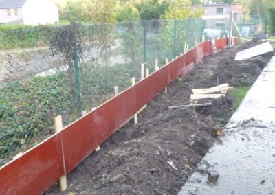 Construction d'un mur de soutien surplombé d'une palissade de béton structuré et placement d'une ...