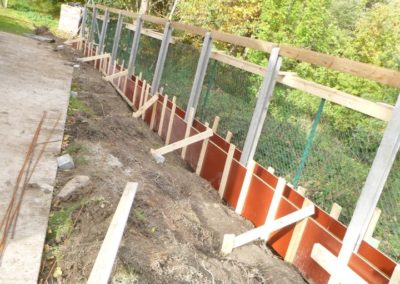 Construction d'un mur de soutien surplombé d'une palissade de béton structuré et placement d'une ...