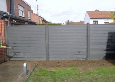 Installation d'une palissade en composite avec une bordure de béton de retenue de terre dans le pie...