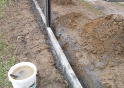 Installation d'une palissade en composite avec une bordure de béton de retenue de terre dans le pie...